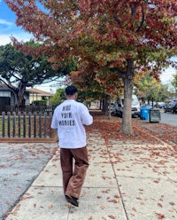 a man walking down a sidewalk wearing a t - shirt